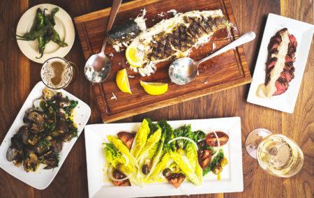 Wood table with food fish grilled lemons and yellow dish