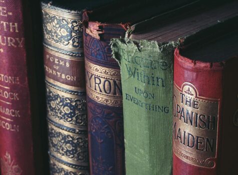 Five antique books standing red black and green in color with gold writing