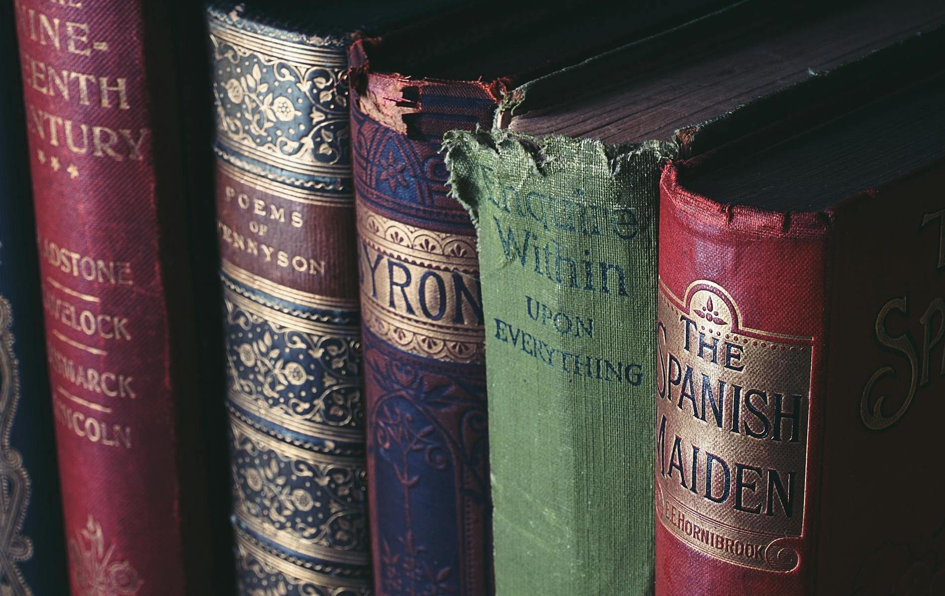 Five antique books standing red black and green in color with gold writing