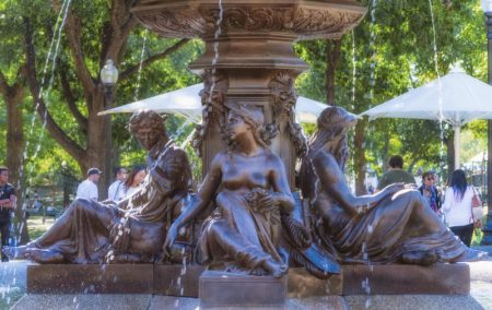 water fountain brown stone base with three women carved into with water flowing