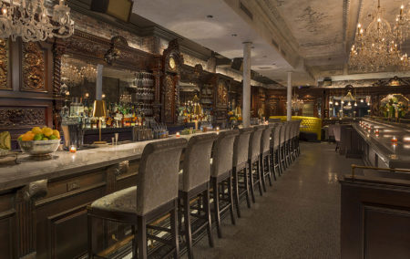 Dark grey bar with 10 chairs and colorful bottle behind bar